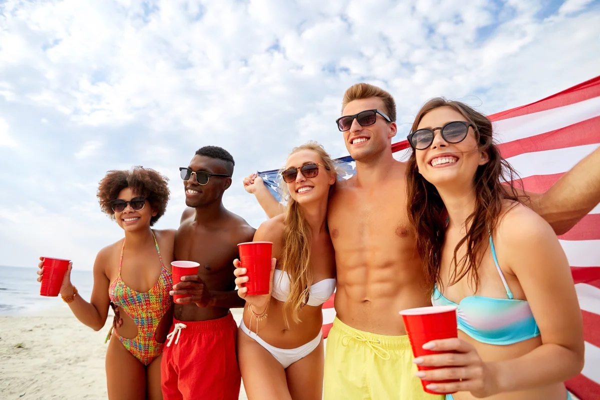 Group of friends celebrating July 4th bar crawl with patriotic drinks and American flags