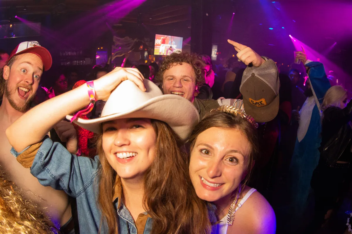 friends dressed in cowgirl and godess costumes at the official halloween bar crawl smiling for a photo