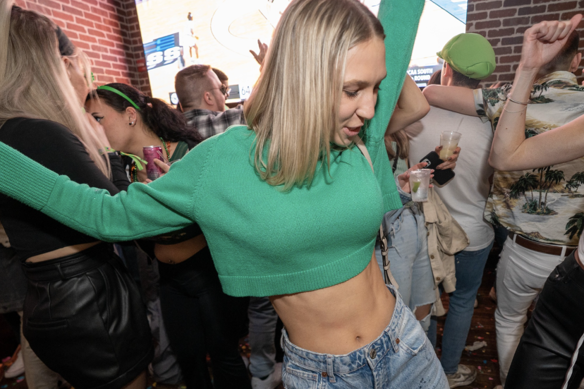 girl smile and holds drink while attending a pub crawl