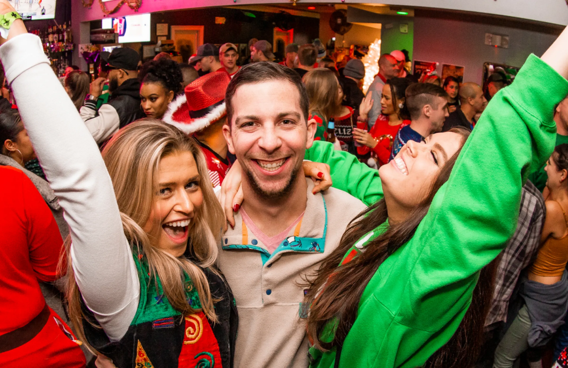 a guy and two girls pose for a picture during the a holiday themed bar crawl