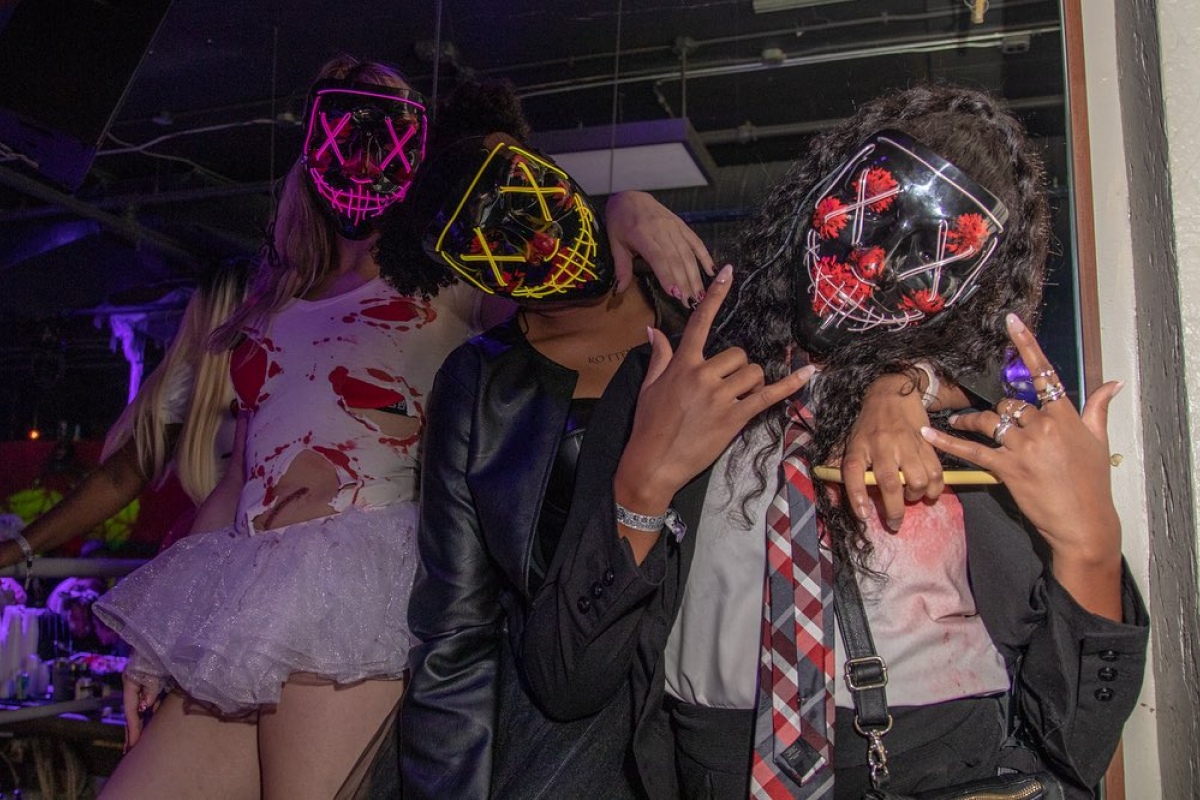 friends wearing halloween masks at a halloween bar crawl dressed up in costume