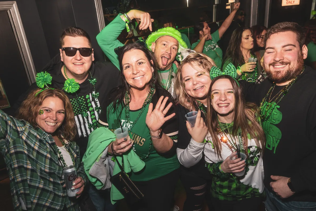 a group of friends smiling during st paddys bar event