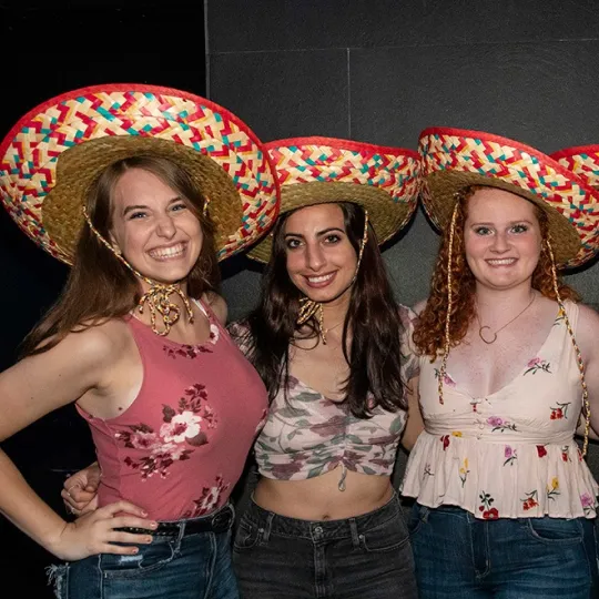 3 girls wearing sombrero hats cheersing margaritas during the tacos and tequila bar crawl
