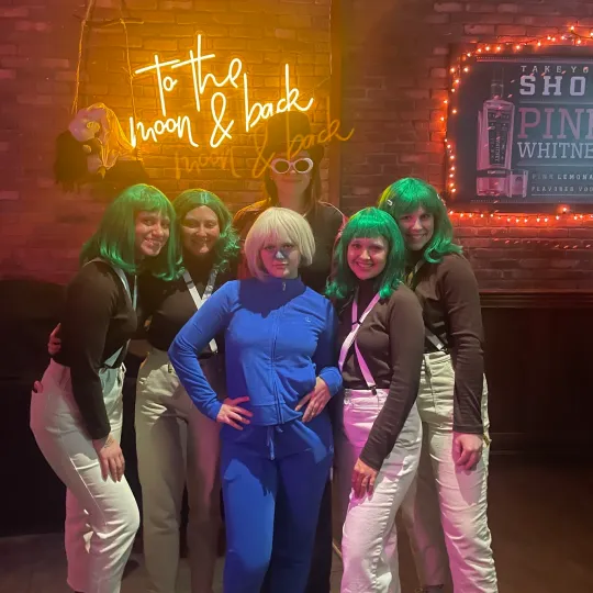 A group of coordinated besties dress as Willy Wonka and The Chocolate Factory's violet and Oopma loompas at one of the best bars in Boston for the Halloween Bar Crawl