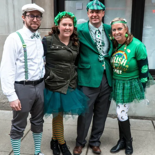 Lively group of friends donning vibrant green outfits, shamrock accessories, and festive hats, immersing themselves in the St. Patrick's Day bar crawl shennanigans
