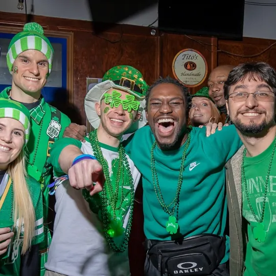 Warm-hearted group of st paddys enthusiasts, each member showing off their creative green gear, savoring the shared experience of the bar crawl's energy