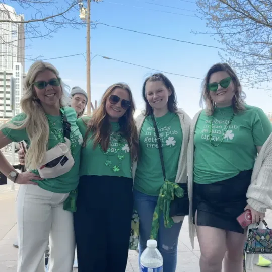 A group of girls outside during check-in for the Charlotte St Pats bar crawl all wearing the same green shirt that reads "Everybody In the Pub Gettin' Tipsy"
