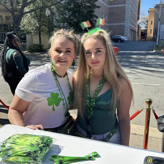 Elated friends in green getting ready to immerse themselves in the lively atmosphere of the St Pddys day bar crawl in Charlotte
