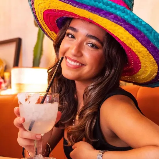 Girl in sombrero hat drinking a margarita during the tacos and tequila bar crawl