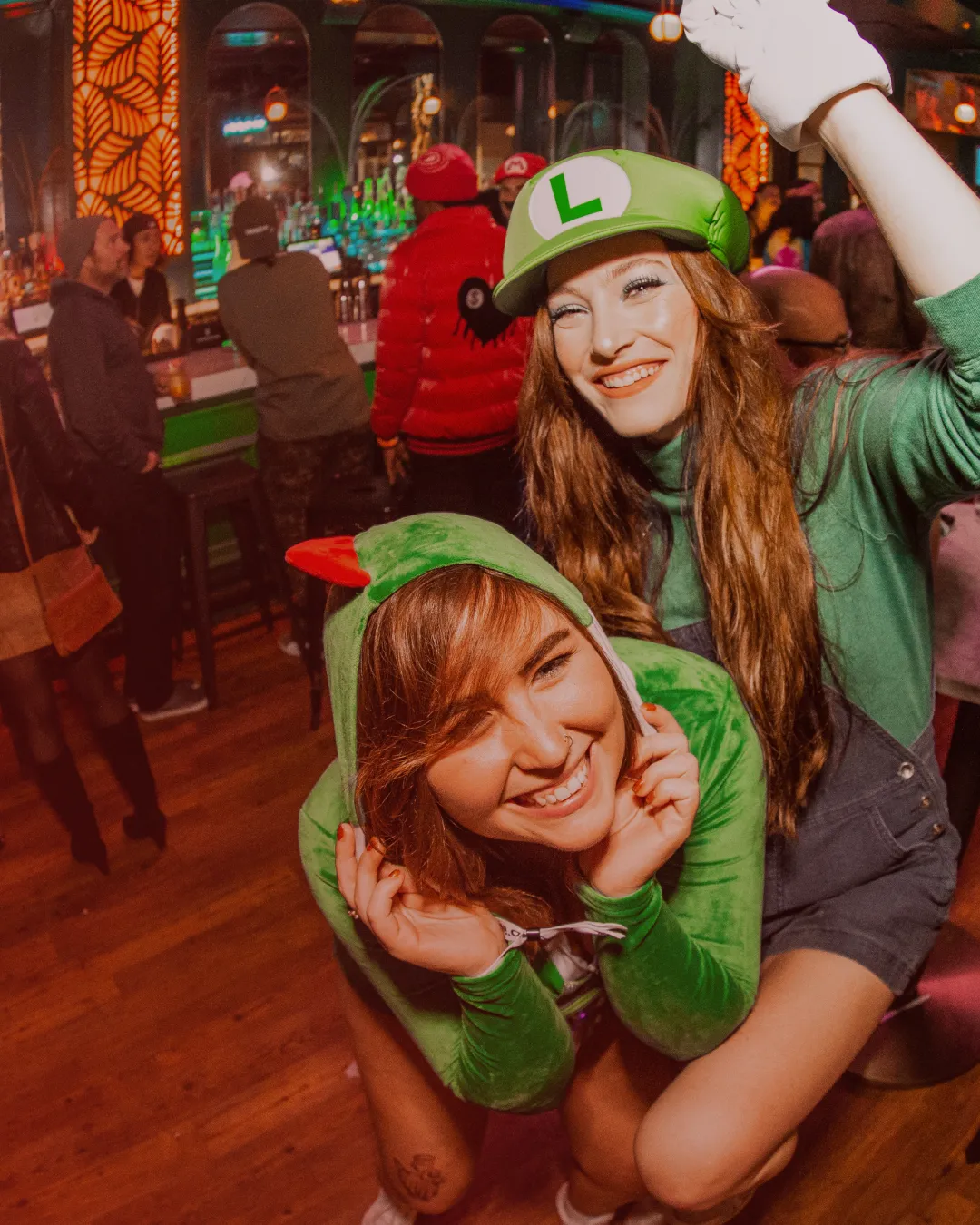 Beneath the bar's dim lighting, a fun friend pair dressed in Mario Cart costumes dance amonst a diverse range of Halloween disguises during the Halloween Bar Crawl
