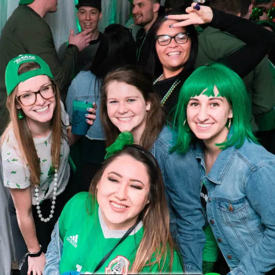 Vibrant cluster of friends, their festive attire dancing with every hue of green, becoming the life and soul of the bar crawl celebration for St Patricks Day