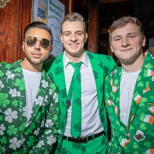 3 young men dressed up in green  shamrock suits and celebrating St Paddys day during the St Pats bar crawl