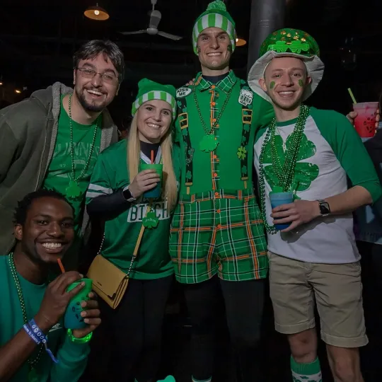 Dynamic group, each adorned with quirky green accessories, creating waves of laughter and joy throughout the St. Patrick's Day bar scene in Cincinnati
