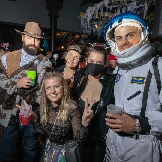 As shadows play on the walls, a group of pals in eclectic Halloween ensembles becomes the epicenter of laughter and spooky tales in the crowded bar for the Halloween Bar Crawl

