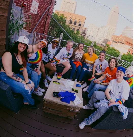 A group of friends circled around a table on Velvet Dog Rooftop in Cleveland during the Pride Bar Crawl