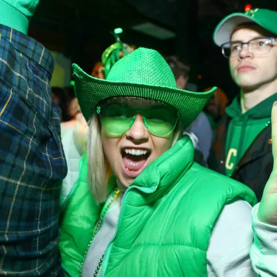 Girl in green glasses and a green cowboy hat and vest celebrating St Paddys day in Cleveland at Barley House