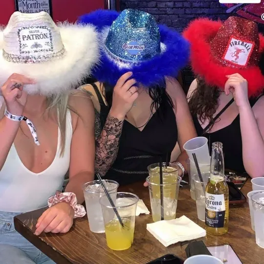 Three girls sitting at Dive Bar in Cleveland during the tacos and tequila bar crawl wearing hats with liquor brands on it