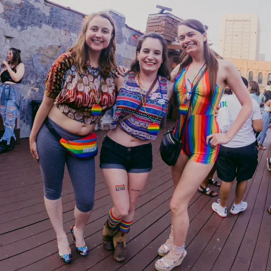 3 girls having a blast at the Pride Bar Crawl celebrating Pride Month wearing their most colorful outfits