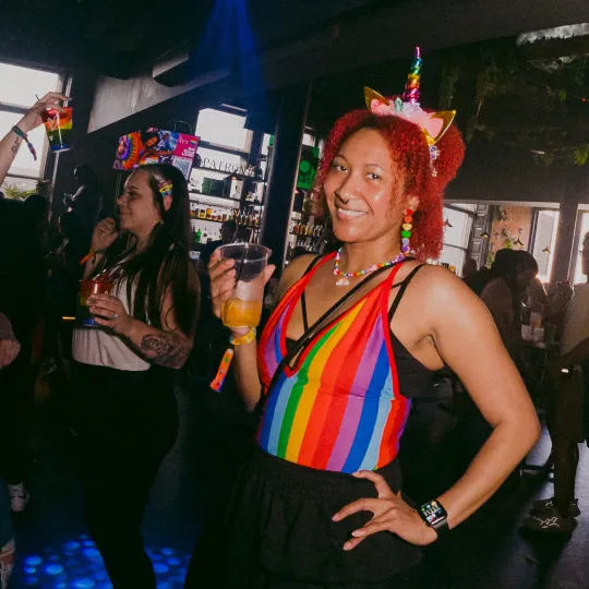 Cute, colorful, and ready to mingle – the Bar Crawl dance floor is where it's at! Girl sips drink.
