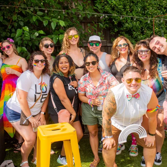 Large friend group feeling bold, looking gold, and rocking rainbow colors at the Pride Bar Crawl

