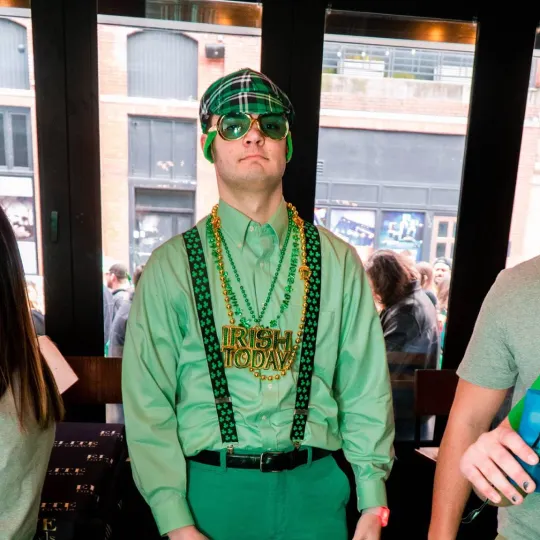 A young man decked out in a green outfit with beads and green glasses during the st paddys day bar crawl