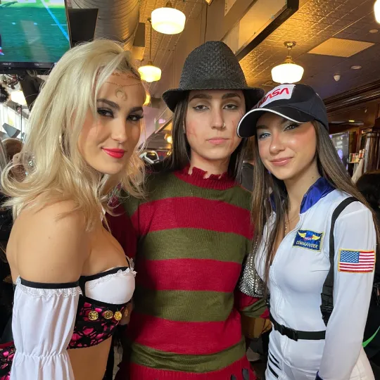 A gathering of gal pals, all decked out in costumes that span the spectrum of Halloween themes, becomes a hub of animation and joy within the bar's setting of the halloween bar crawl in Hoboken

