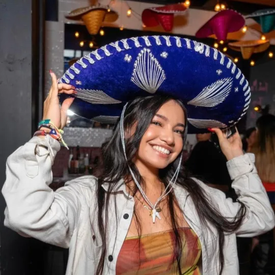 Girl holding her sombrero hat and happy ready to crawl from one bar to the next at the Tacos and tequila bar crawl