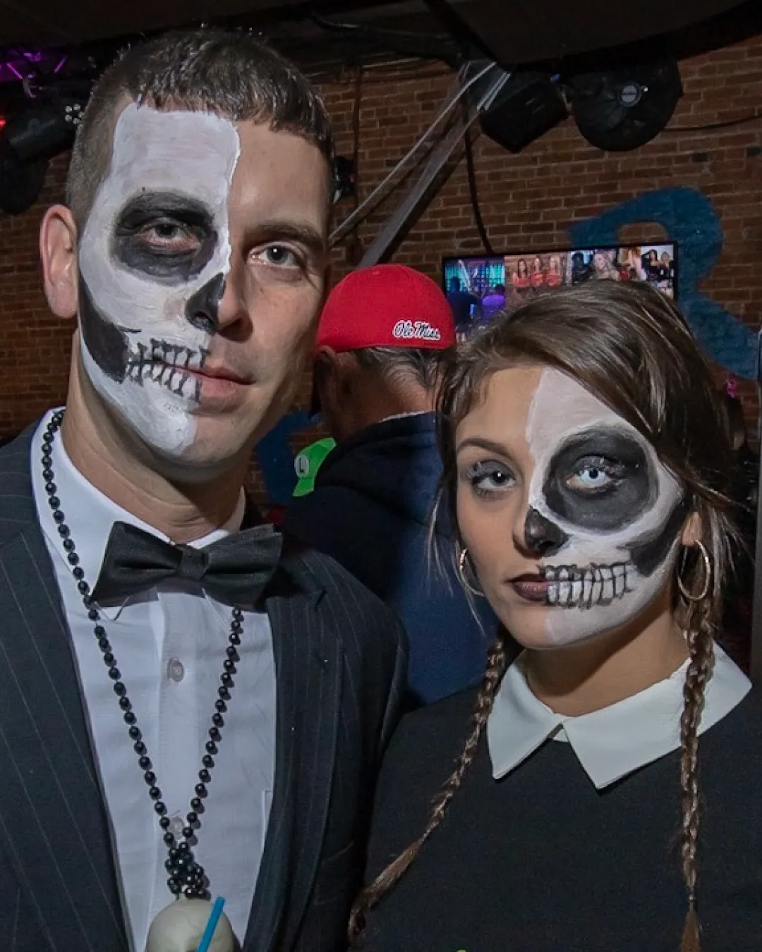 In the heart of the bar's energetic atmosphere, a couple united in their halloween makeup stand out, weaving spookiness with every move
