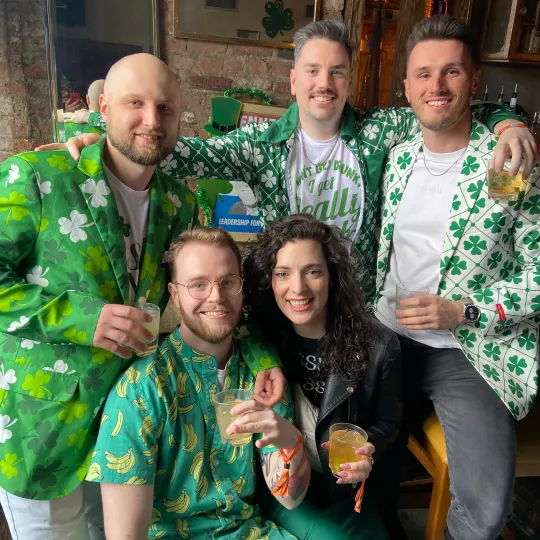 Warm-hearted group, their outfits sprinkled with four-leaf clovers, embracing the camaraderie and merriment of the themed bar crawl for St Patricks Day
