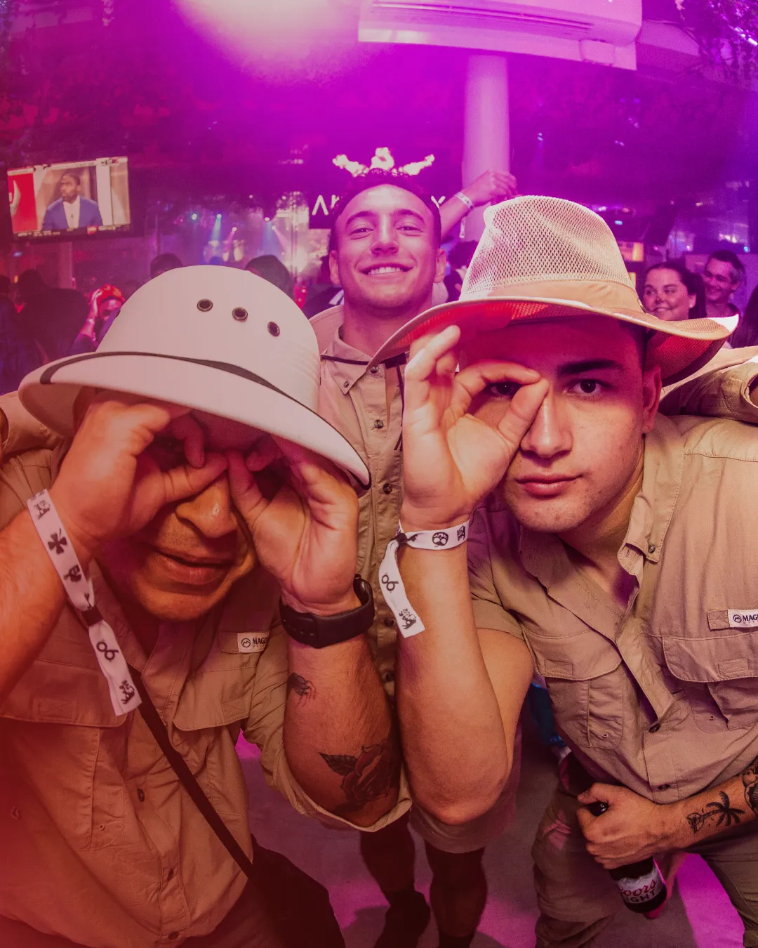 Amidst the Halloween energy, a group of young gentleman dressed and ready for a safari pose for the camera making binoculars with their hands and enjoy the fun of the halloween bar crawl
