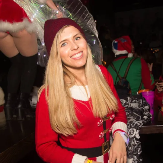 A smiling christmas bar crawler having a blast in her Santa Onesie