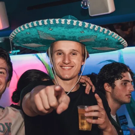Young gentleman in an iconic sombrero, standing out and soaking in the euphoria of the Tacos and Tequila bar crawl festivities
