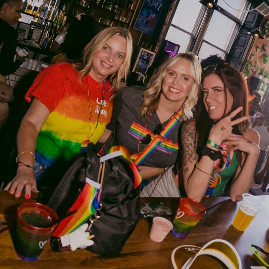 3 colorful friends ordering drinks at the Pride Bar Crawl