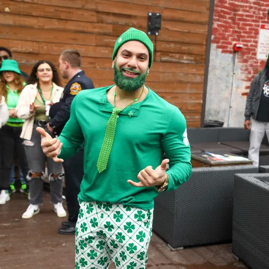 Person in a striking green ensemble, radiating confidence as they pose against the backdrop of the club's booming energy

