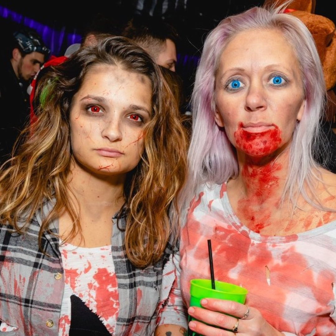 2 girls dressed in zombie makeup staring into the camera looking angry during the halloween bar crawl