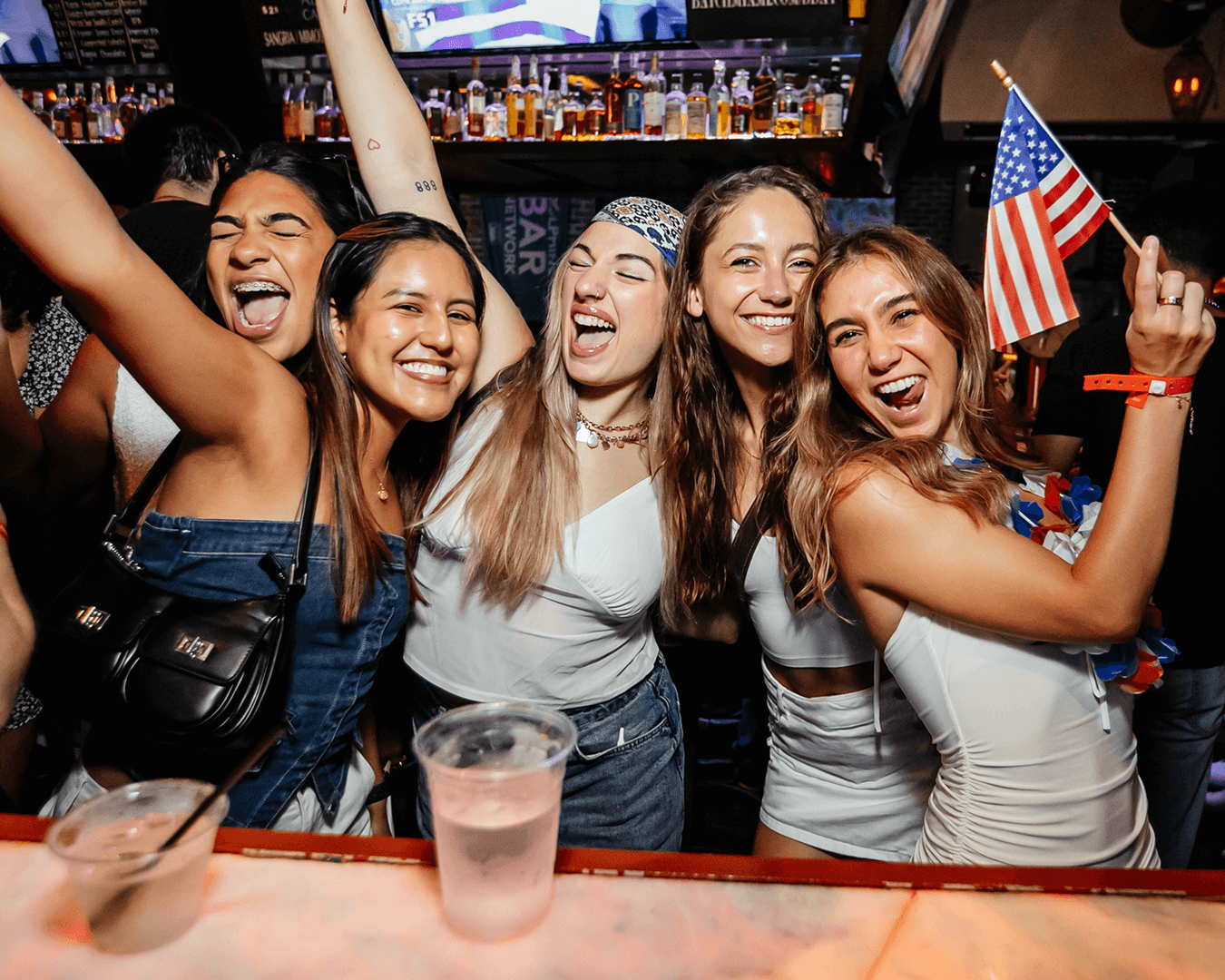 a girl holds up margaritas and smiles at the cinco de mayo bar crawl
